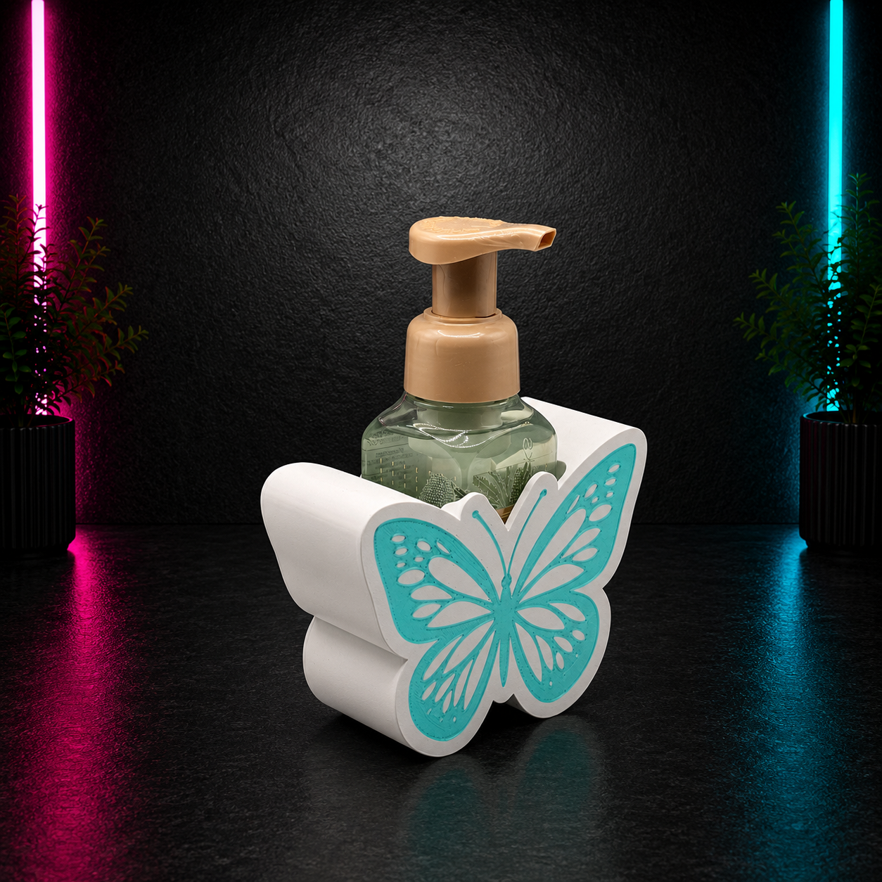 White butterfly soap holder with teal butterfly detail holding a foaming soap bottle on a dark neon pink and blue background by Chaotic Glow Studio.